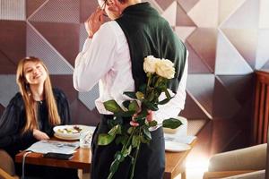 garçom dá flores para uma mulher. dentro do novo restaurante de luxo moderno foto