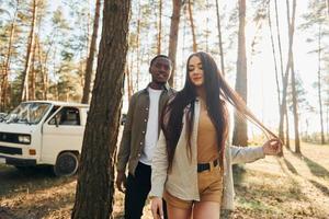 ônibus está atrás. jovem casal está viajando na floresta durante o dia juntos foto