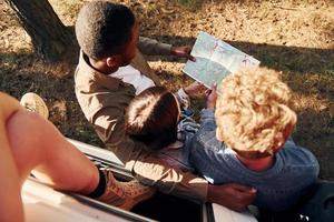 segurando o mapa e procurando a localização. grupo de jovens está viajando juntos na floresta foto