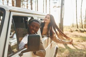 sentado no carro. jovem casal está viajando na floresta durante o dia juntos foto