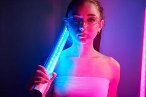 com equipamentos de iluminação. jovem elegante em pé no estúdio com neon foto