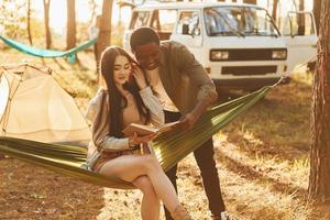 lendo um livro. jovem casal está viajando na floresta durante o dia juntos foto