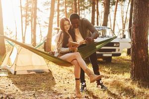 lendo um livro. jovem casal está viajando na floresta durante o dia juntos foto