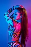 mulher confiante em roupas coloridas em pé no estúdio com luz neon foto