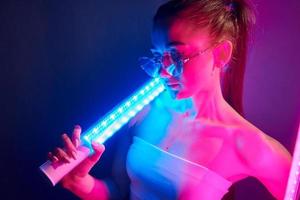 com equipamentos de iluminação. jovem elegante em pé no estúdio com neon foto