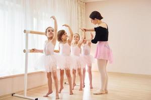 treinador ensina crianças. pequenas bailarinas se preparando para o desempenho praticando movimentos de dança foto
