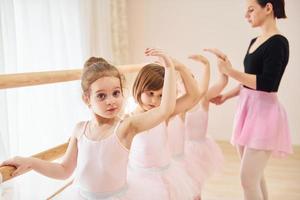 mulher ensina passos de dança. pequenas bailarinas se preparando para performance foto