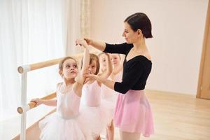 trabalhando com treinador. pequenas bailarinas se preparando para o desempenho praticando movimentos de dança foto