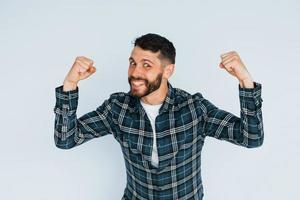 comemorando o sucesso. jovem em roupas casuais em pé dentro de casa no estúdio foto