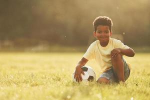 iluminada pela luz solar. garoto afro-americano divirta-se no campo durante o dia de verão foto