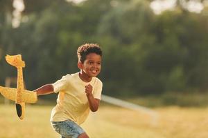 com brinquedo nas mãos. garoto afro-americano divirta-se no campo durante o dia de verão foto