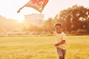 pipa vermelha. garoto afro-americano divirta-se no campo durante o dia de verão foto