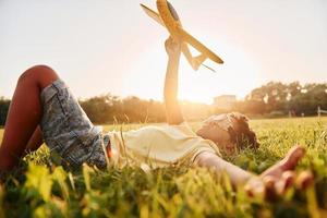 menino com avião de brinquedo. garoto afro-americano divirta-se no campo durante o dia de verão foto