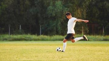 prática profissional. jovem jogador de futebol tem treinamento no campo esportivo foto