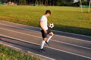 segura a bola na mão. jovem jogador de futebol tem treinamento no campo esportivo foto