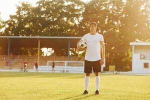 de pé e posando. jovem jogador de futebol tem treinamento no campo esportivo foto