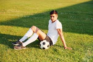 faz uma pausa. jovem jogador de futebol tem treinamento no campo esportivo foto