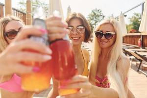 bebendo coquetéis. mulheres em trajes de banho se divertem juntas ao ar livre no verão foto