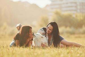 duas mulheres com cachorro estão se divertindo no campo durante o dia ensolarado foto