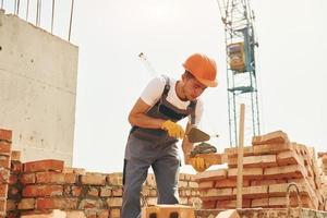 jovem trabalhador da construção civil de uniforme está ocupado no prédio inacabado foto