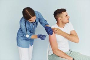 usando seringa. médico de uniforme fazendo vacinação para o paciente foto