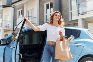 com sacola de compras. jovem em roupas casuais com seu eletromóvel ao ar livre durante o dia foto