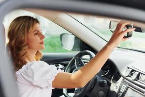 jovem em roupas casuais está sentada em seu carro durante o dia foto