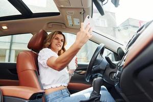 concepção de sucesso. jovem em roupas casuais está sentada em seu carro durante o dia foto