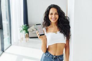 interno doméstico. mulher alegre com cabelo preto encaracolado está dentro de casa foto