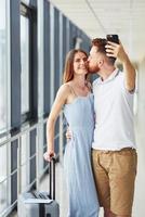 casal feliz. jovem viajante está no hall de entrada do aeroporto foto