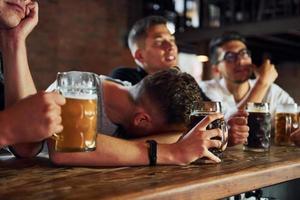 vista lateral de amigos com cerveja. pessoas em roupas casuais sentadas no pub foto