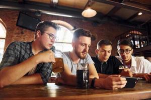 vista lateral de amigos com cerveja. pessoas em roupas casuais sentadas no pub foto