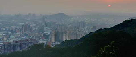 vista de uma cidade ao pôr do sol de uma montanha foto