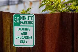 sinal de estacionamento de 30 minutos de metal velho e desbotado com texto verde foto