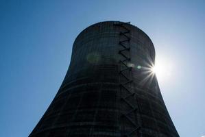 torre de resfriamento nuclear sob um céu azul com um sunburst foto