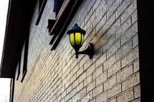 lâmpada montada em uma parede de tijolos iluminando a luz dourada foto