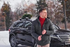 homem com pequeno abeto verde está ao ar livre perto de seu carro. concepção de férias foto