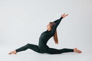 alongamento lateral. jovem em roupas esportivas fazendo ginástica dentro de casa foto