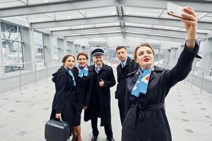 fazendo selfie. tripulação de avião de uniforme vai trabalhar juntos foto