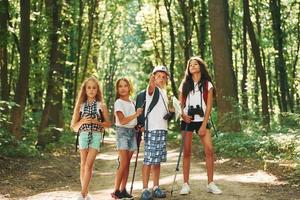 bela luz do sol. crianças passeando na floresta com equipamentos de viagem foto