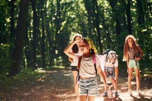 menina olhando para longe. crianças passeando na floresta com equipamentos de viagem foto