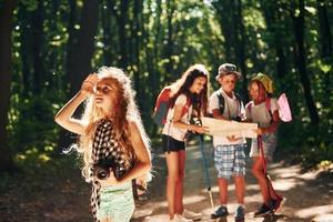 menina olhando para longe. crianças passeando na floresta com equipamentos de viagem foto