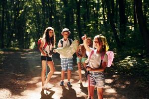 posando para a câmera. crianças passeando na floresta com equipamentos de viagem foto