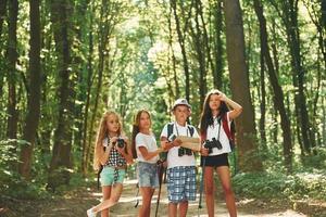 atividades de fim de semana. crianças passeando na floresta com equipamentos de viagem foto