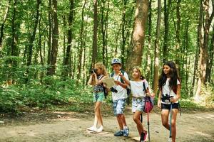fim de semana de verão. crianças passeando na floresta com equipamentos de viagem foto