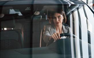 veículo de cor preta. mulher testando carro novo. sentado dentro de casa no automóvel moderno foto