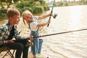 se divertindo. menino com sua irmã na pesca ao ar livre no verão juntos foto