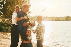 concepção de férias. pai e mãe com filho e filha pescando juntos ao ar livre no verão foto