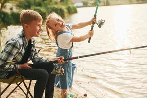 se divertindo. menino com sua irmã na pesca ao ar livre no verão juntos foto