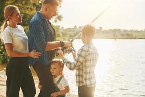 concepção de férias. pai e mãe com filho e filha pescando juntos ao ar livre no verão foto